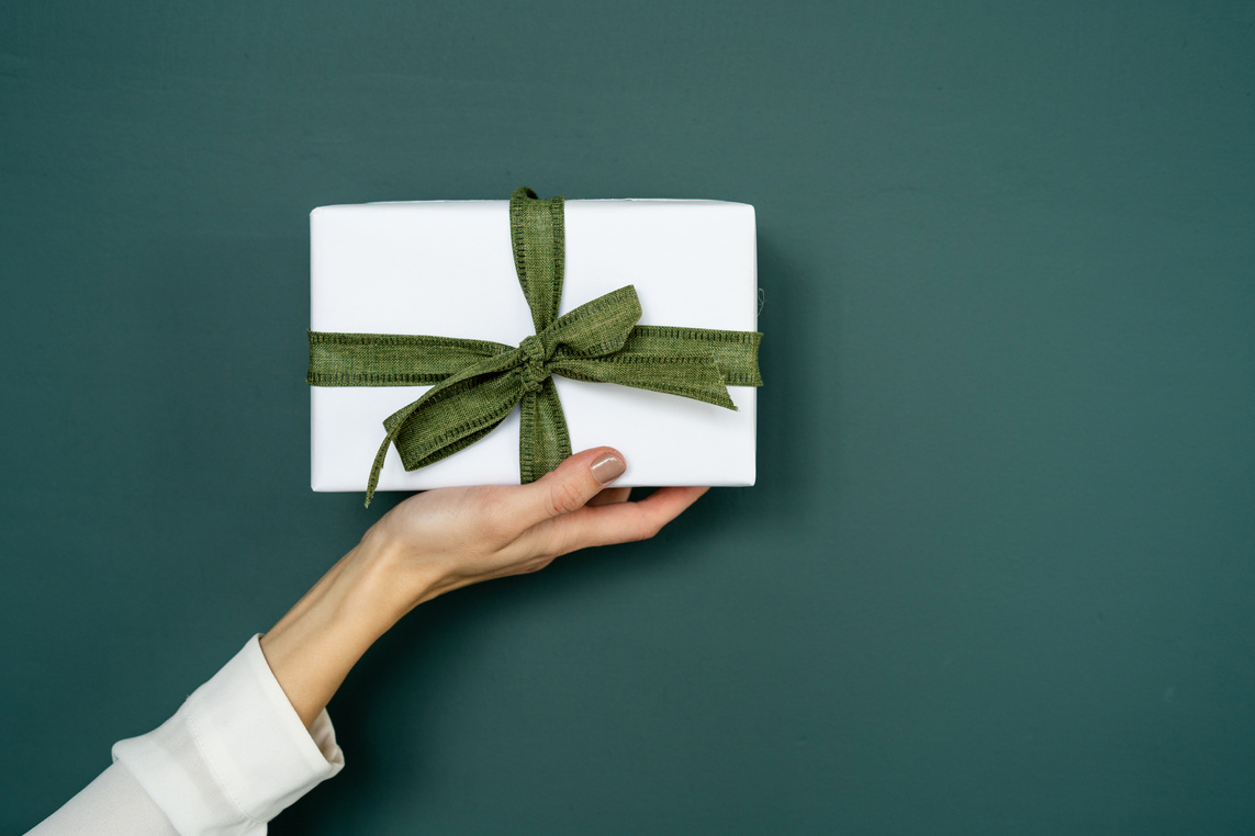 Woman holding present on green background